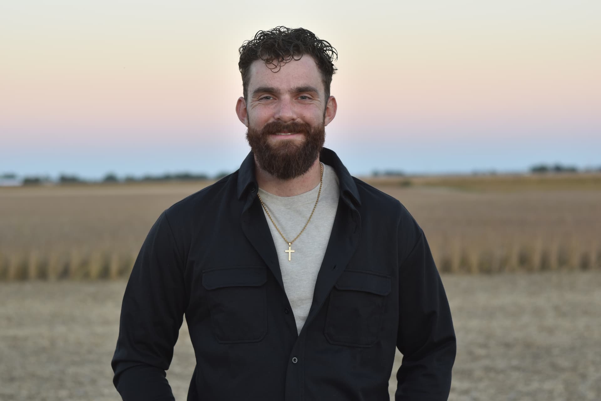 Gabe Kassab of Crestone Homes standing in an Indiana farm field at sunset